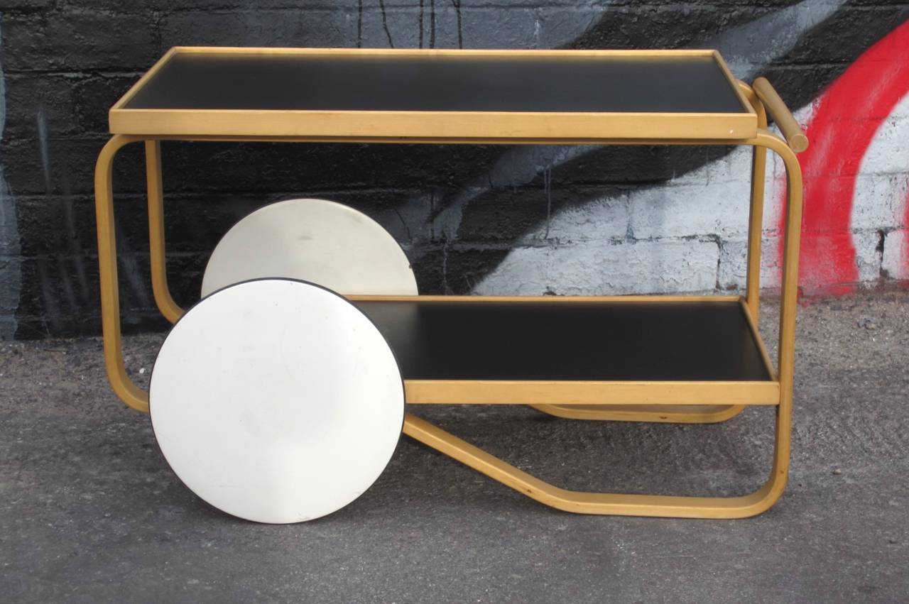 Serving Bar cart designed by Alvar Aalto for Alivar in natural birch with black tray tops.
Killer design, quality crafted.
Shows very little use with just a few scratches.