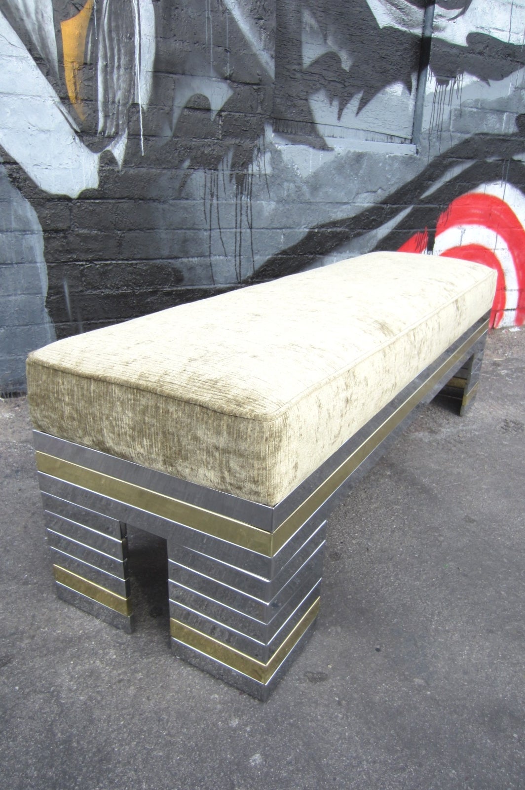 circa 1970's steel bench with individual plated bands of chrome and brass in the manner of Paul Evans cityscape design. We couldn't find any other examples of this bench anywhere. 
Long(5 ft.) and narrow gallery style bench with cushy upholstered