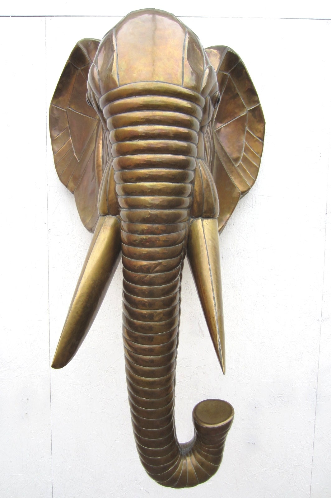 Huge life size elephant head wall sculpture by artist Sergio Bustamante.
 Sculpted in hammered brass with a dark golden aged patina. Measures 5-1/2' tall and 3' wide.
Excellent condition.
