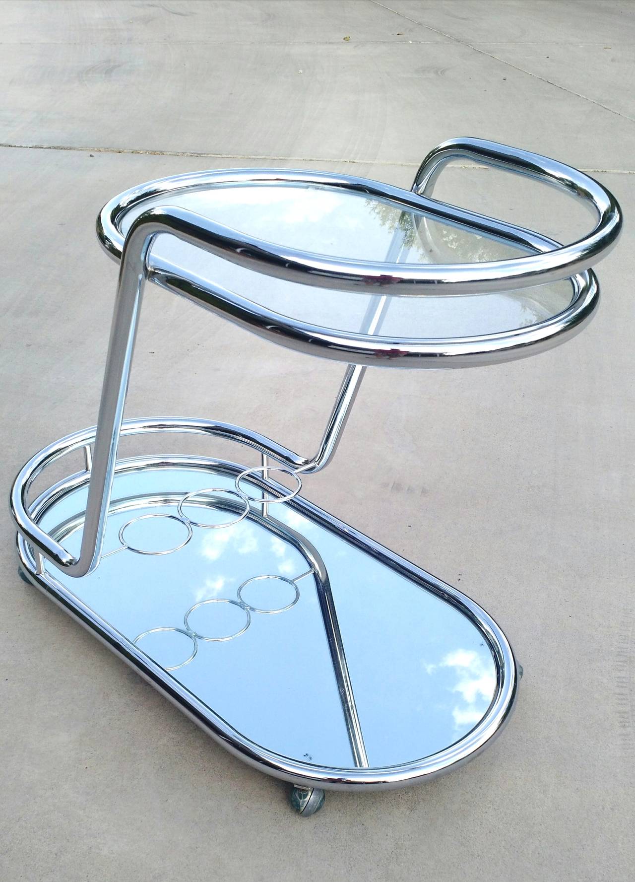 Gleaming bar cart with cantilever design, circa 1970s
Sculpted out of seamless chrome plated steel tubing with
glass top shelf and mirrored glass bottom. 3 ring bottle holder on bottom.
Killer piece! Un-signed by designer.
