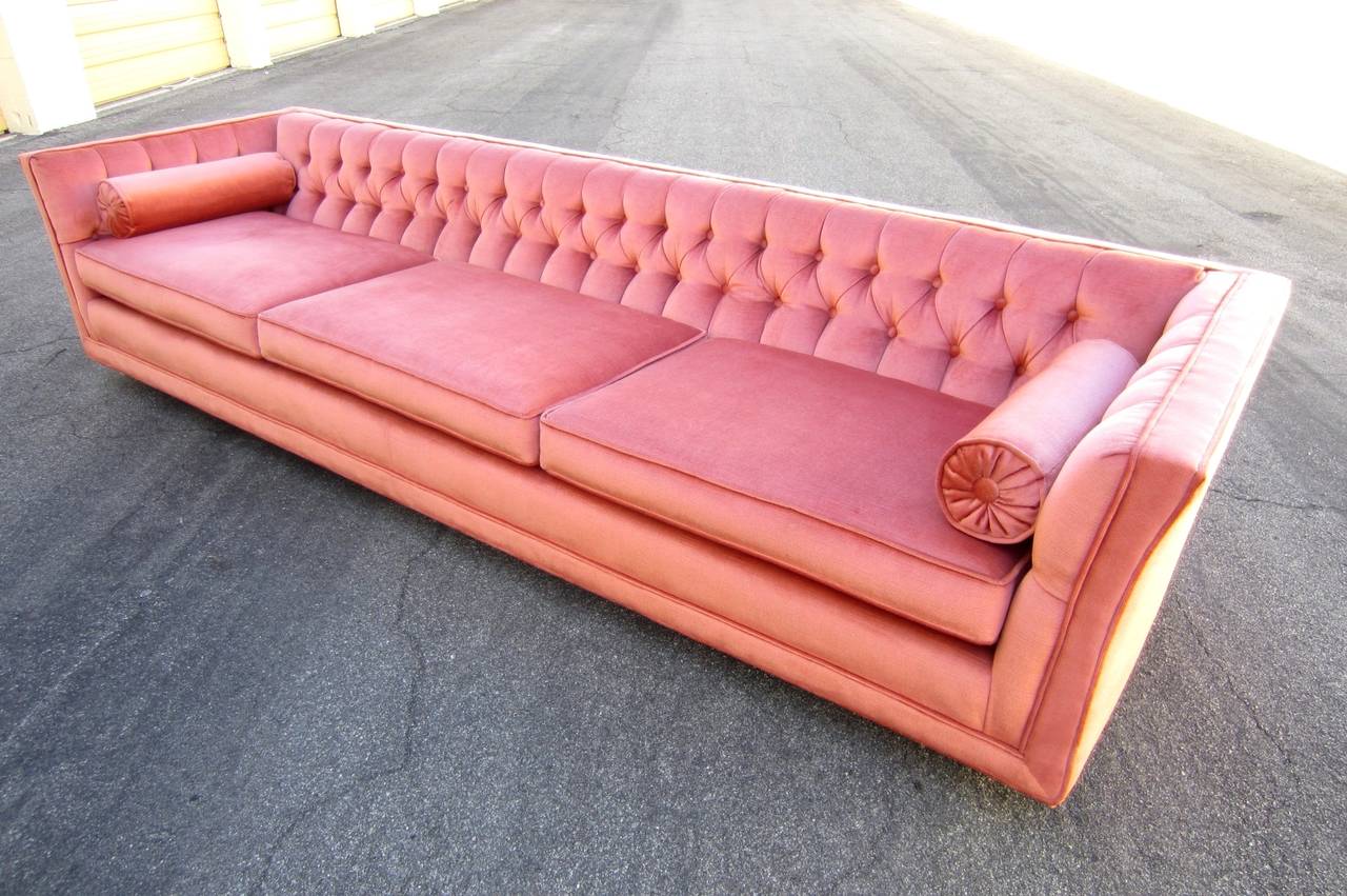 Offered is a matching pair of velvet tufted sofas measuring 9 feet long.
Circa 1960s, both in minty fresh condition from a fabulous old Las Vegas estate.
Gorgeous salmon/coral colored cotton velvet. They sit low and roll on 5 brass casters. The