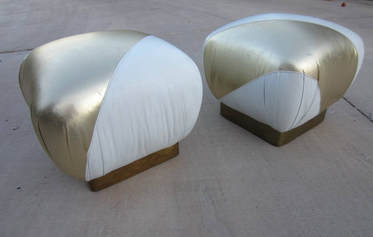 Pair of vintage Karl Springer style Pouf stools upholstered in asymmetrical metallic gold and white leather with brass trimmed bases,
circa 1970s.