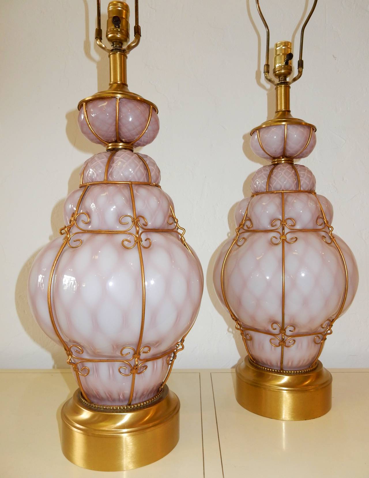 Gorgeous pair of Italian hand blown cage art glass table lamps in a beautiful pinkish violet color.
Gleaming brass plated cage, top and base.