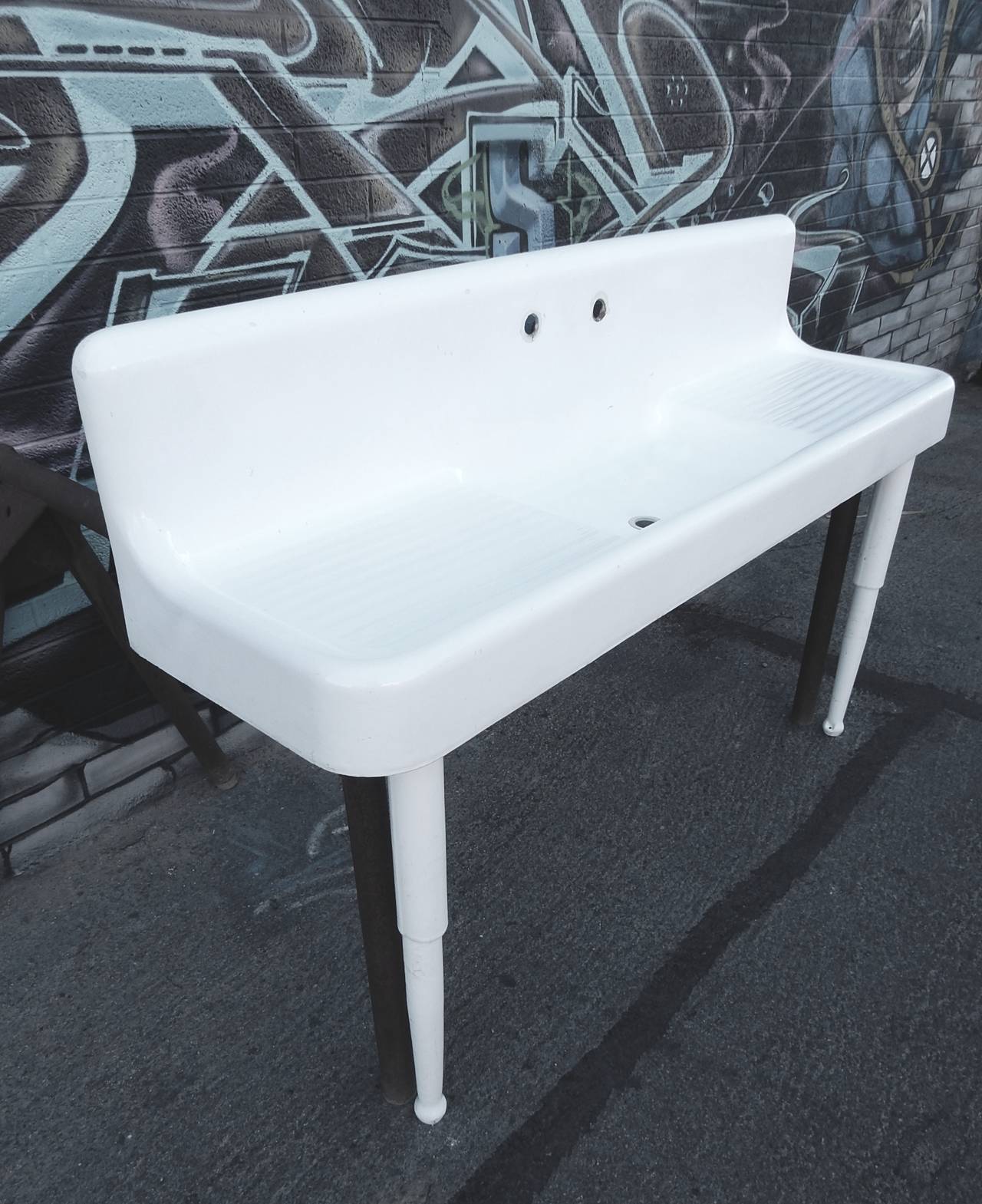 Huge 1930s high back double drain board cast iron farm sink in white porcelain.
Includes two front legs as shown.