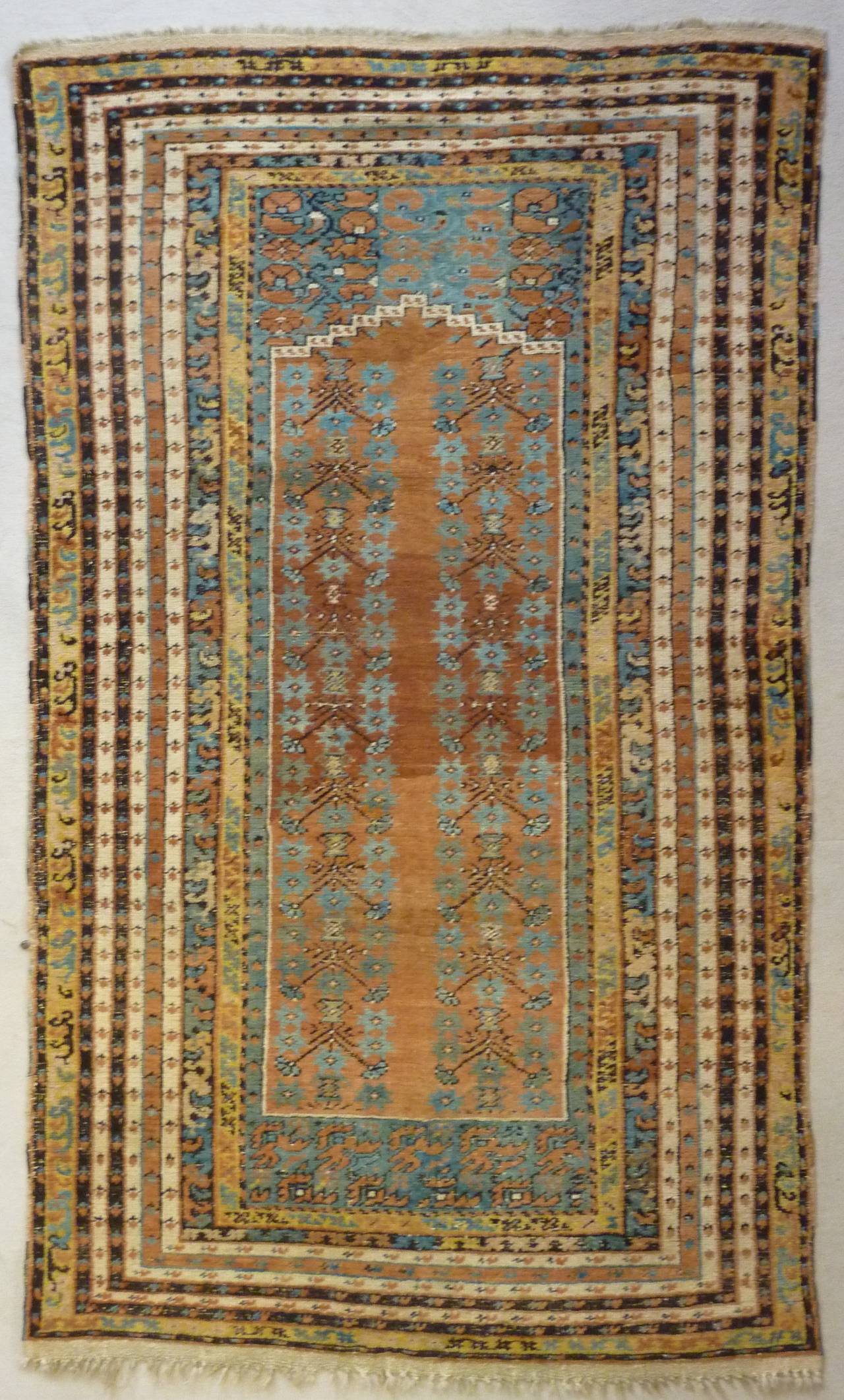 This old Anatolian Koula prayer carpet is hand-knotted in Kula, a town at the east of Izmir, in western Turkey. 

Highly elaborated through a floral composition in which bees and carnations are presented on the numerous small borders. Tree of