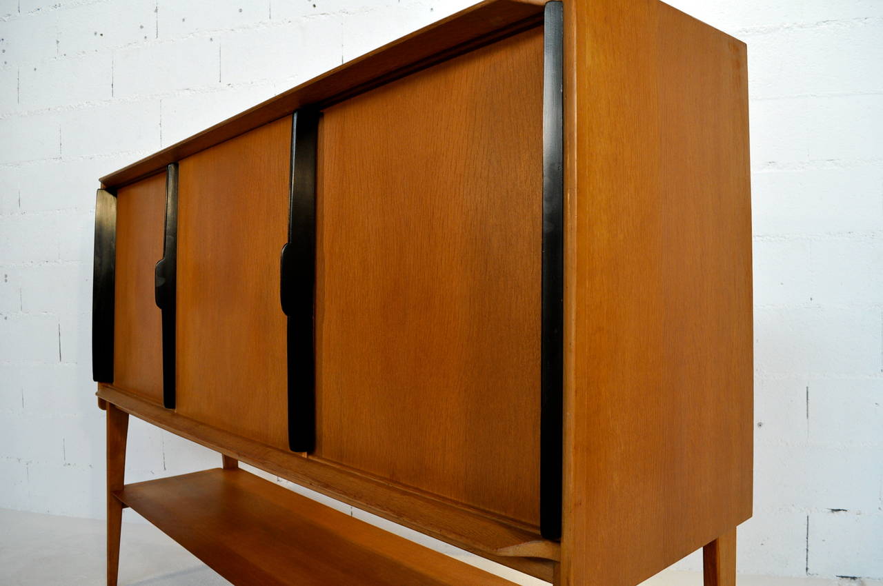 Oak highboard by Roger Landault for Meubles ABC Editor in 1957. Oak frame and panel with black laquered pulls. Good original condition.