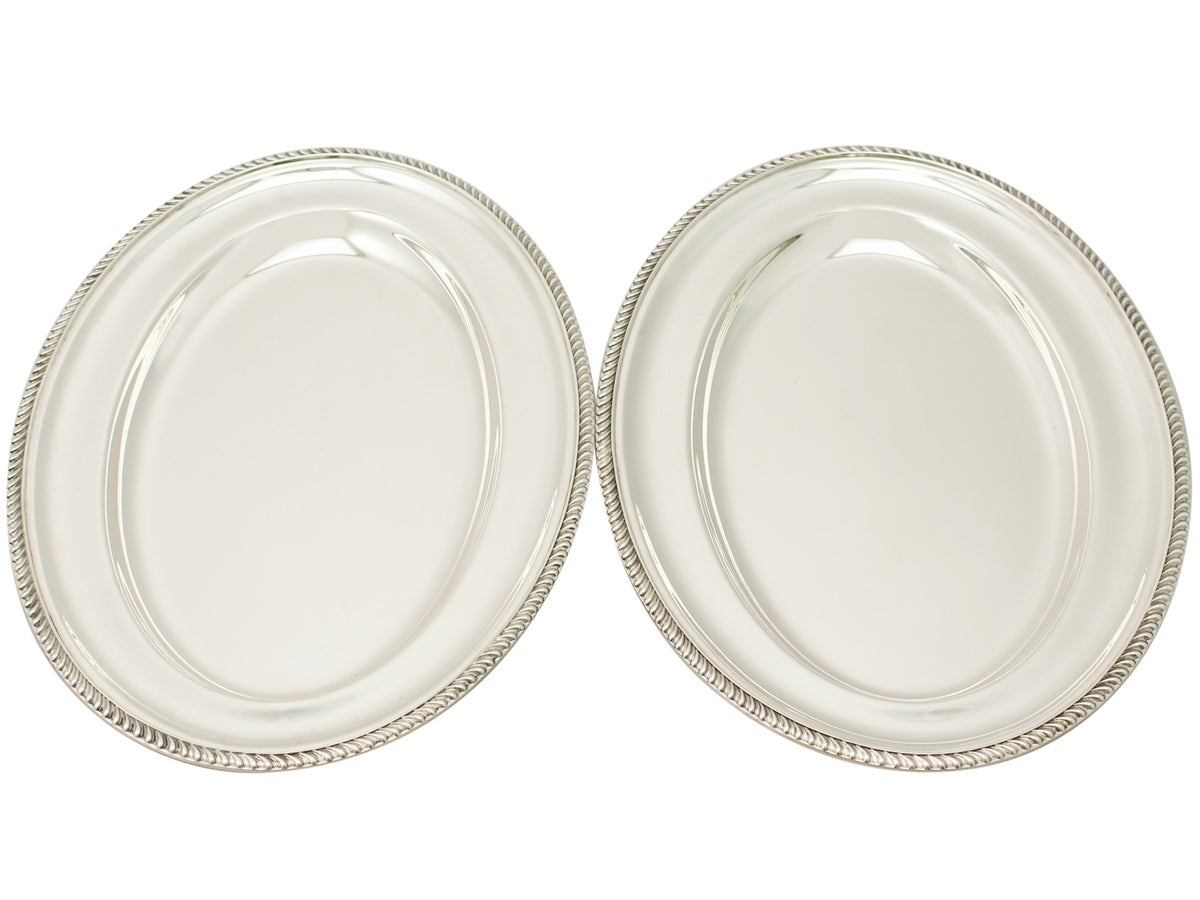 A fine and impressive pair of antique George V English sterling silver meat platters; part of our dining silverware collection.

These fine antique George V sterling silver meat platters have a plain oval form.

Each platter is encompassed with