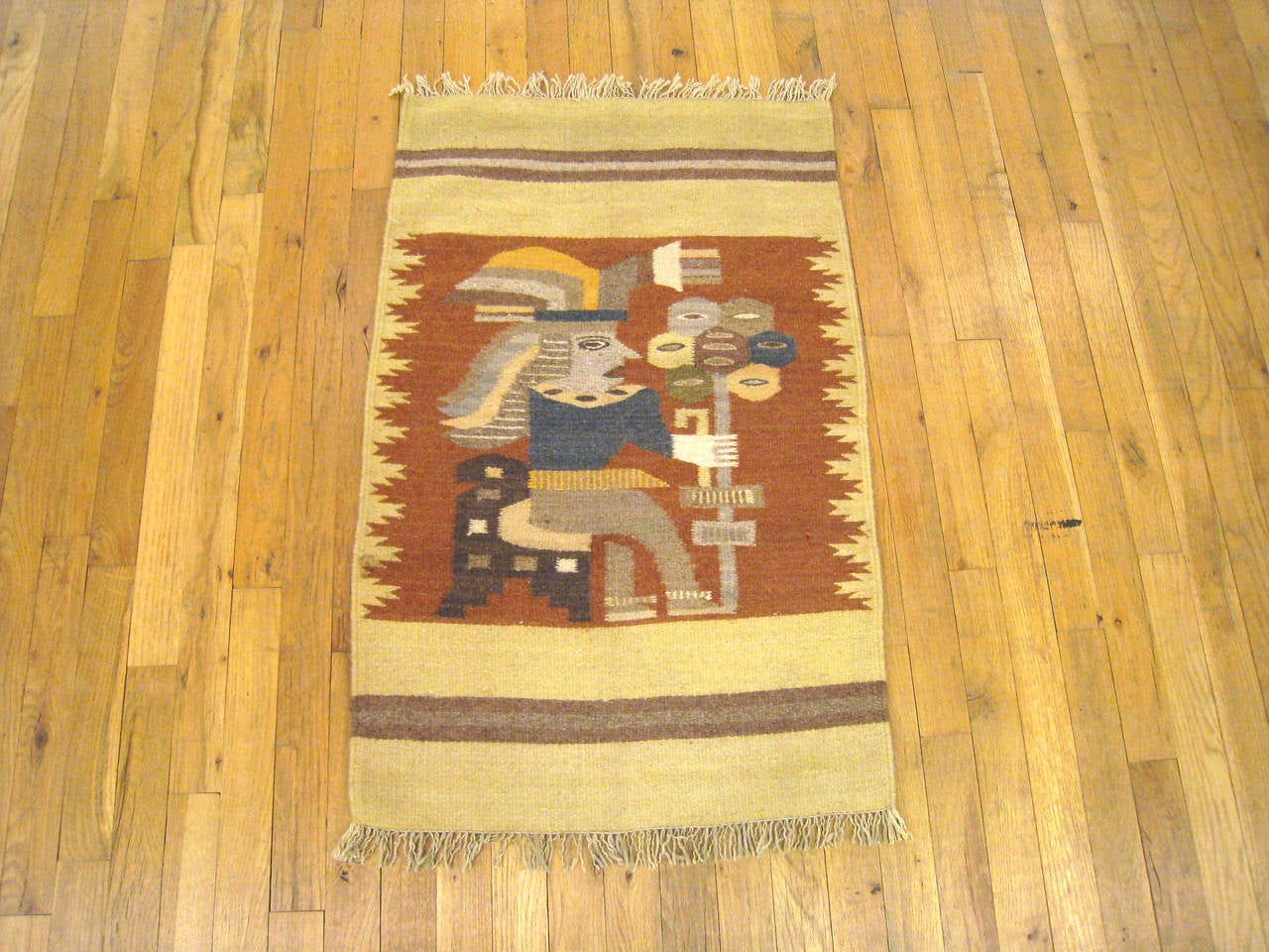 A vintage pictorial rug from the Zapotec Indian tribe in Oaxaca, Mexico, size 3' x 2', depicting a stylized figure seated and wearing a ceremonial headdress, holding a staff with seven hexagonal elements on it. The figure appears in a central