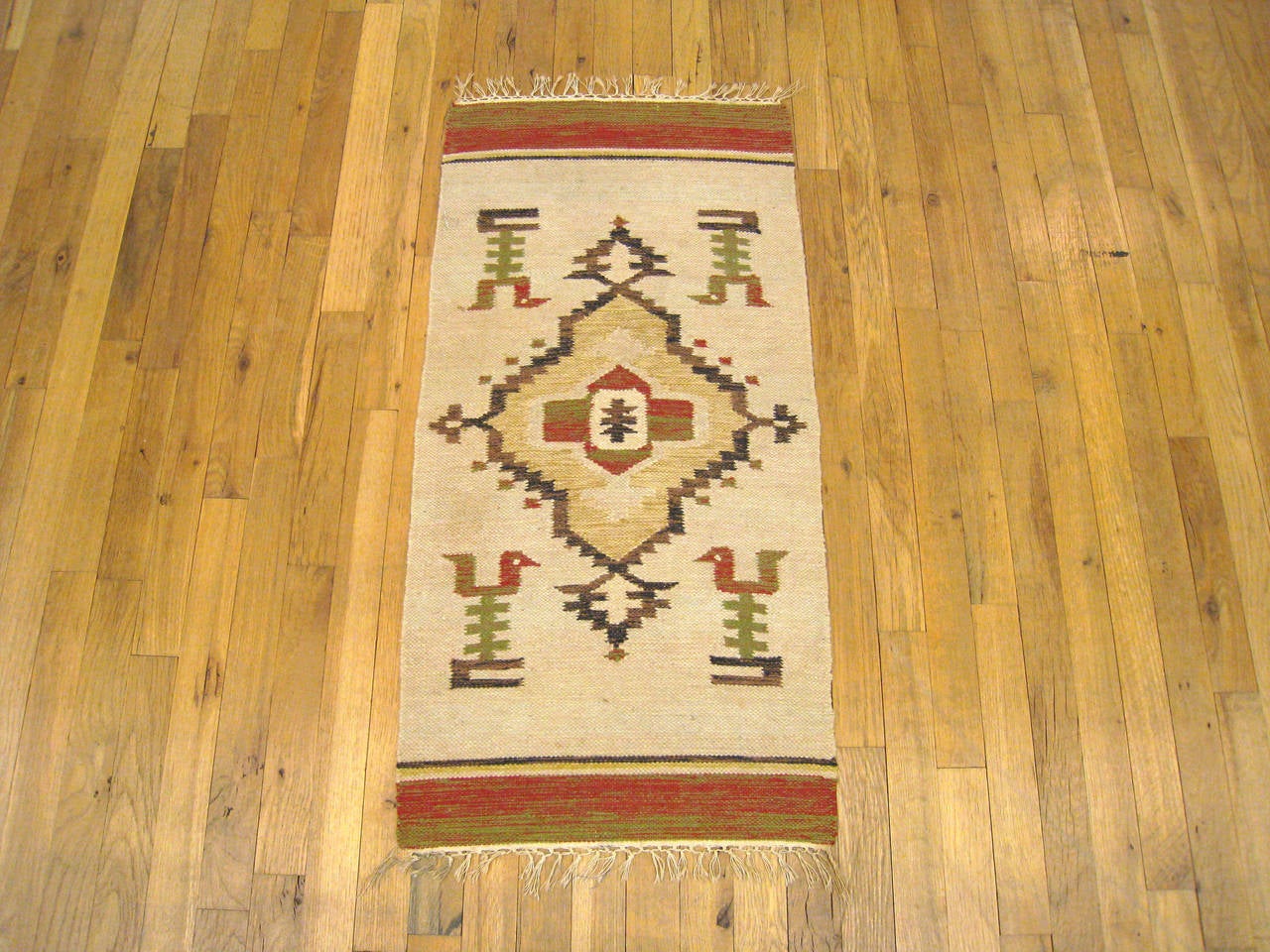A vintage decorative rug from the Zapotec Indian tribe in Oaxaca, Mexico, size 3'3 x 1'8, featuring a central medallion on an unfussy beige field, with four stylized bird motifs standing at each of the four corners. The main field is bordered on