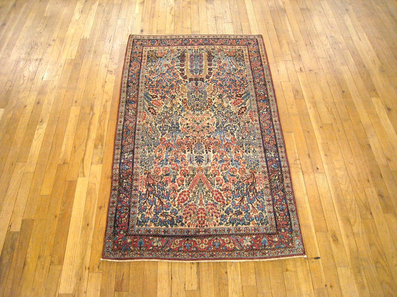 An antique Persian Kerman oriental rug, circa 1900, size 5' x 3'. This fine hand-knotted rug features a densely populated floral central field, with a wide variety of flowering motifs filling the field from end to end. This lushly designed carpet