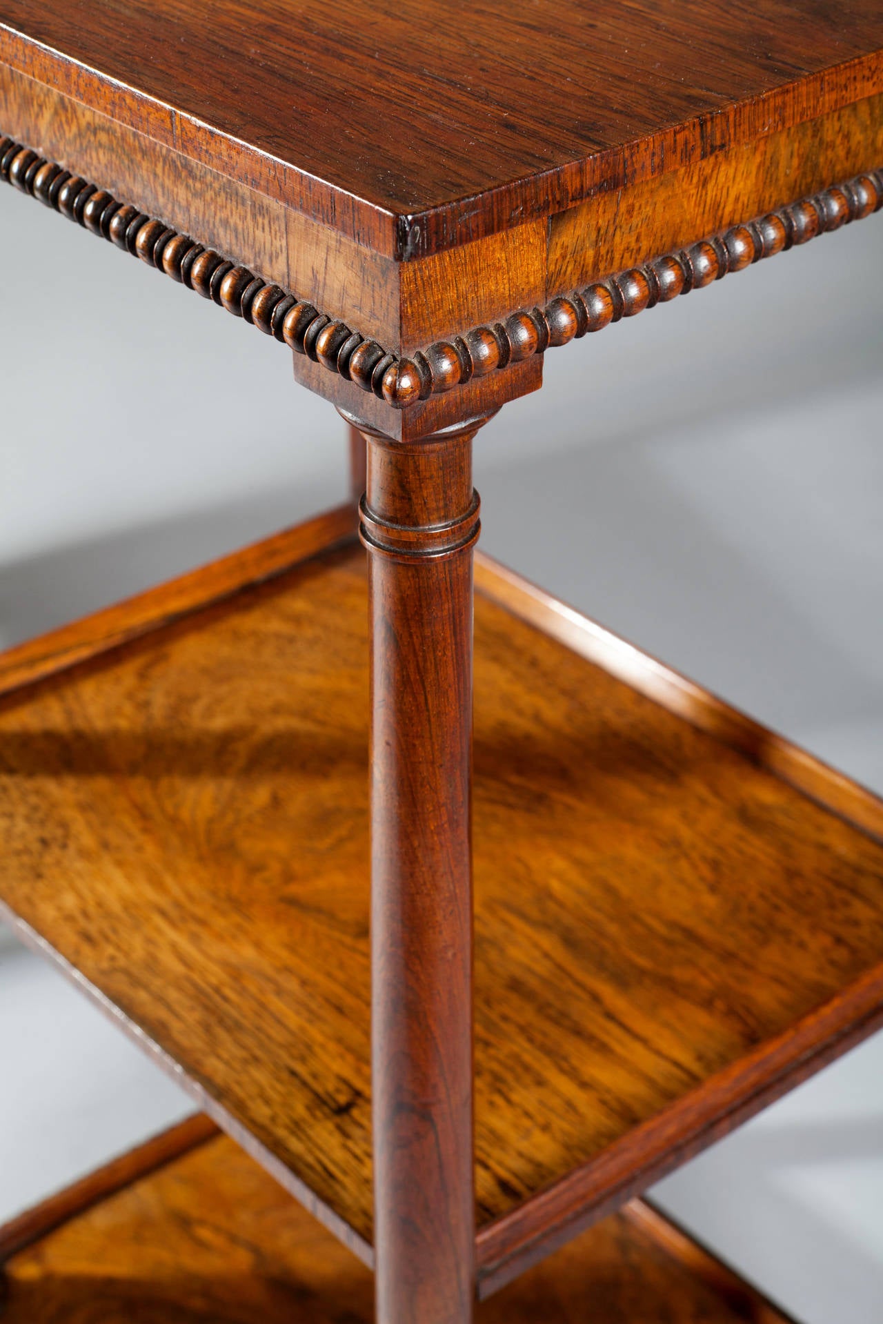 A fine pair of early 19th century well figured rosewood etageres, consisting of three tiers, the upper and lower tier with egg and dart moulding to the edges, each etagere raised on turned tapering feet.