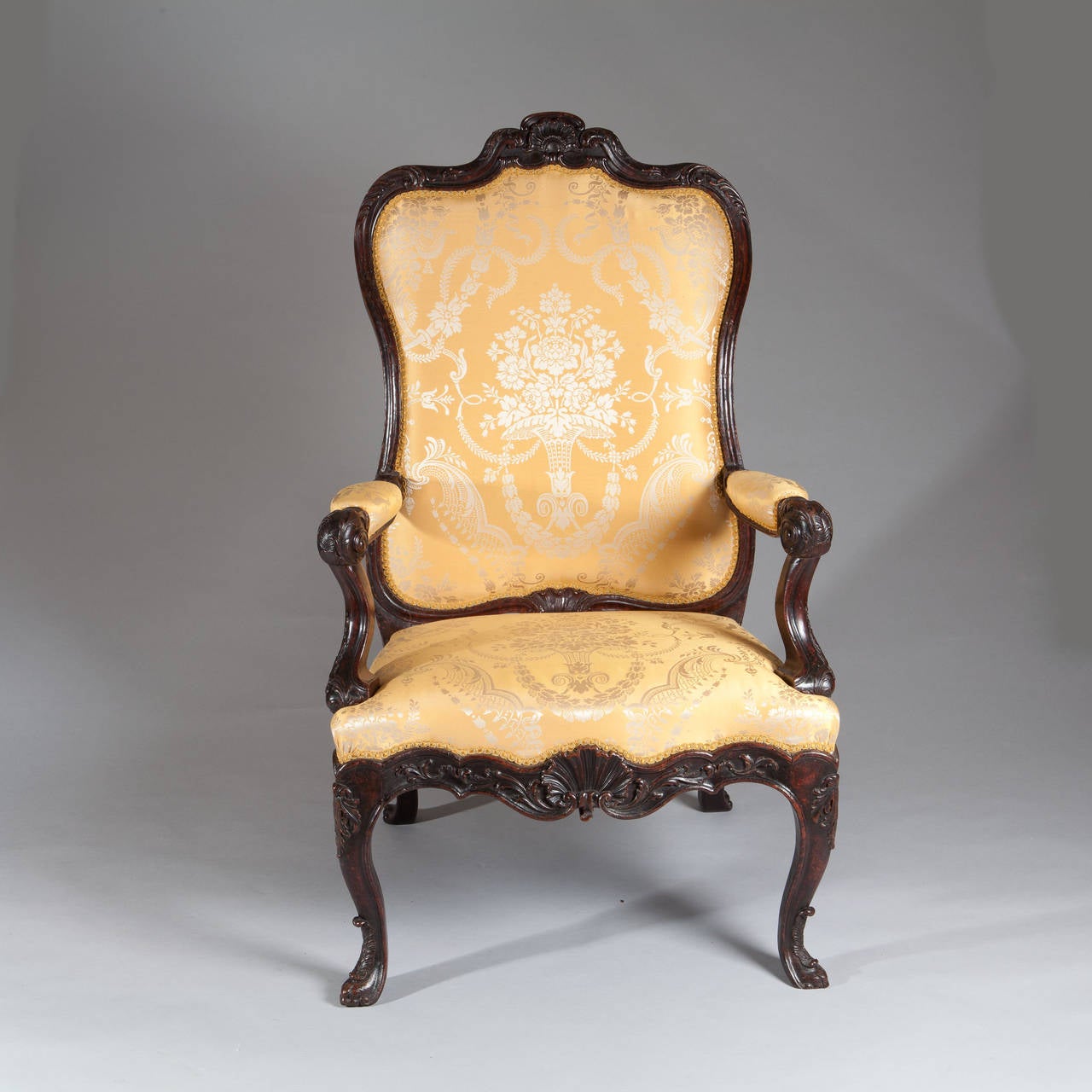 A fine 18th century large-scale armchair, boldly carved with Rococo ornament, the shaped top rail with central shell motif leading to outswept arms, the whole raised on cabriole legs the surface with acanthus and foliate carving.