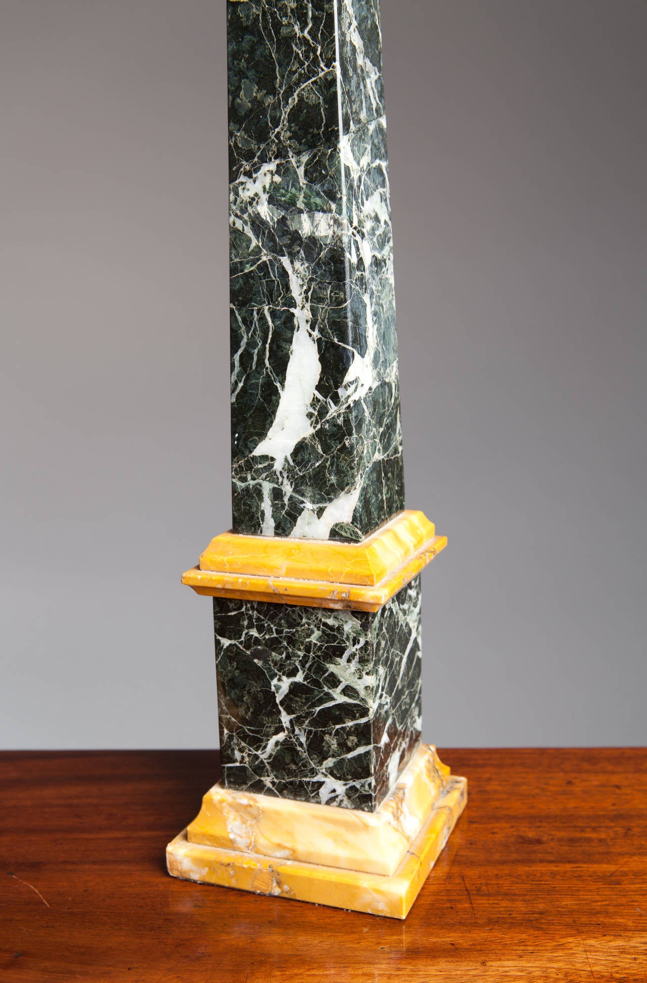 A pair of classical obelisks in a polished green marble and Sienna marble.