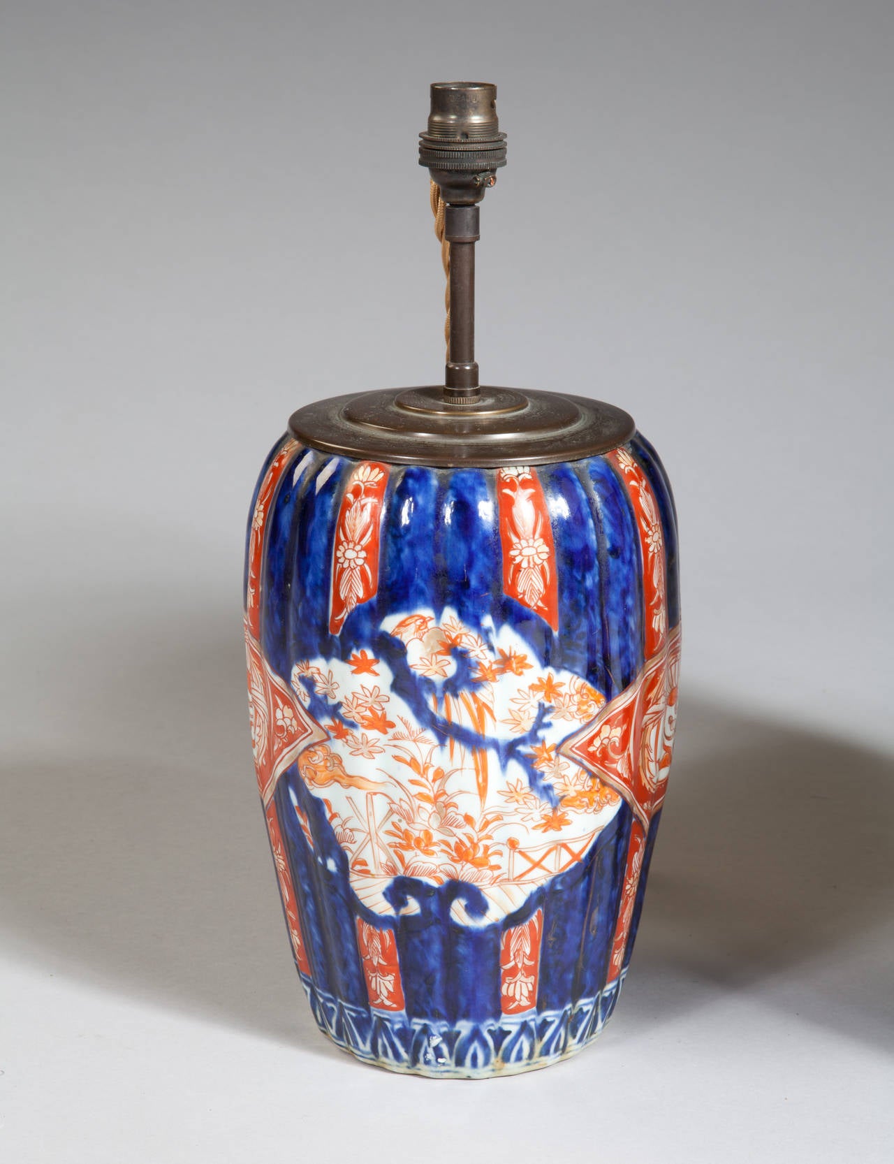 A fine pair of late 19th century Japanese Imari vases now mounted as lamps. The bulbous bodies decorated in coral orange, blue and white are slightly ribbed and taper towards the base. 

Offered with the white and black card shades shown.