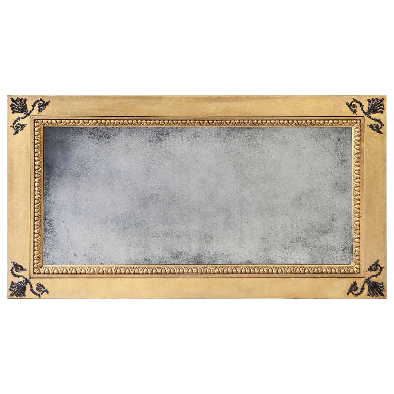 A rare and unusual Regency parcel-gilt mechanical patent overmantel mirror. The outer frame is enriched at the corners with bronze patinated anthemia supported by scrolls against a sanded gilt ground. The inner frame is bordered with an egg and dart