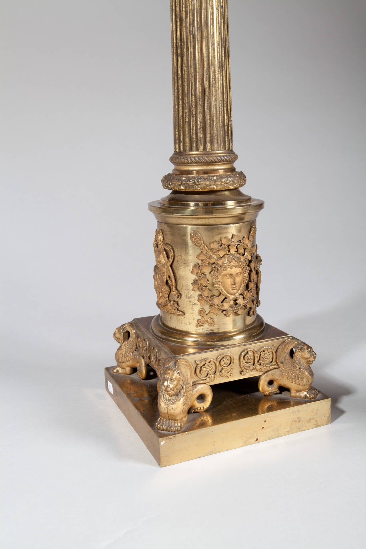 Ein außergewöhnliches Paar monumentaler Säulenlampen aus vergoldeter Bronze, jede mit kannelierten Säulen, fein ziselierten korinthischen Kapitellen und aufgesetzten klassischen Masken und Beschlägen am Sockel.