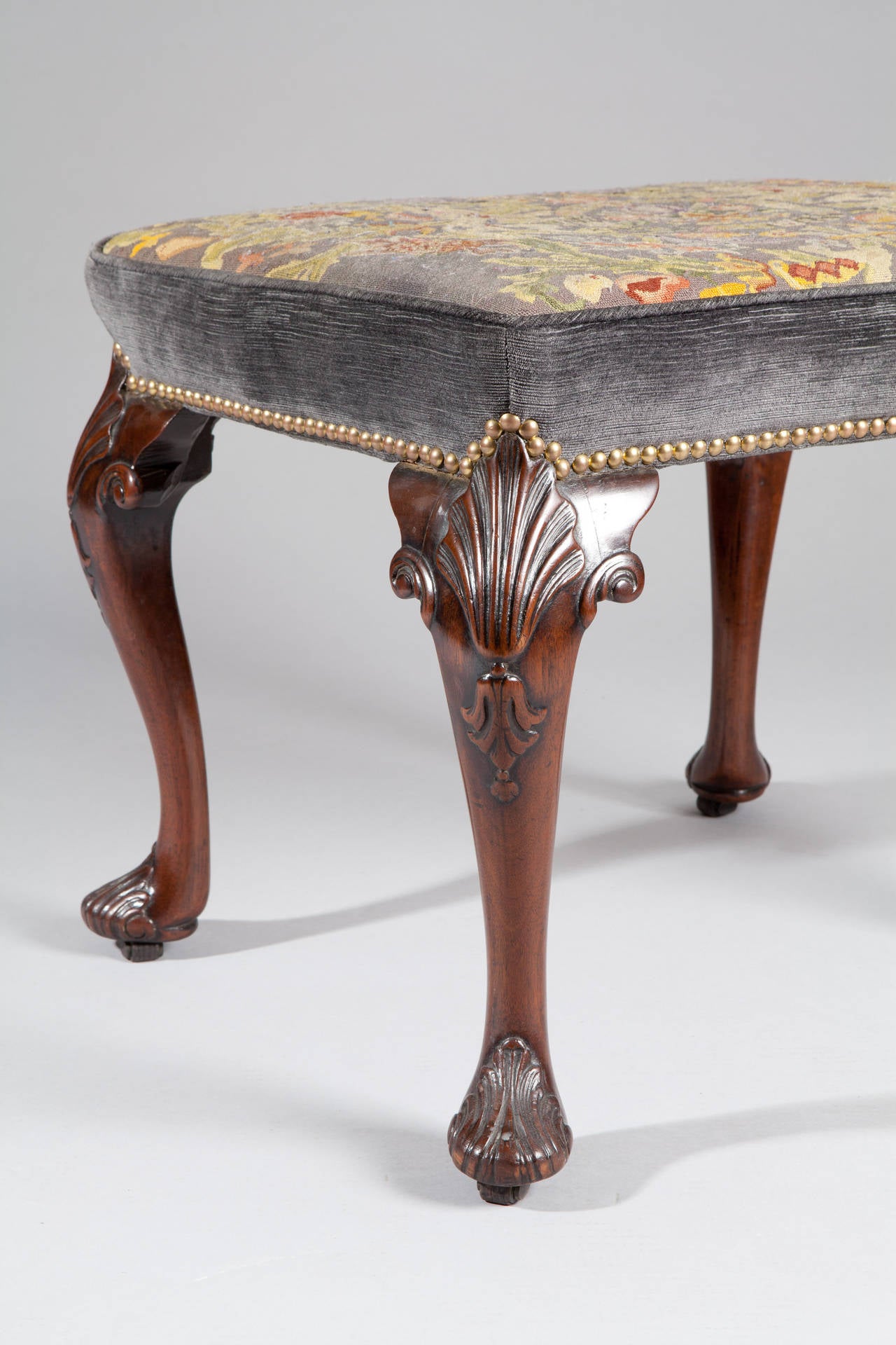 A fine mid-18th century walnut stool raised on cabriole legs terminating in pad feet, the seat upholstered in a later petit point needlework.