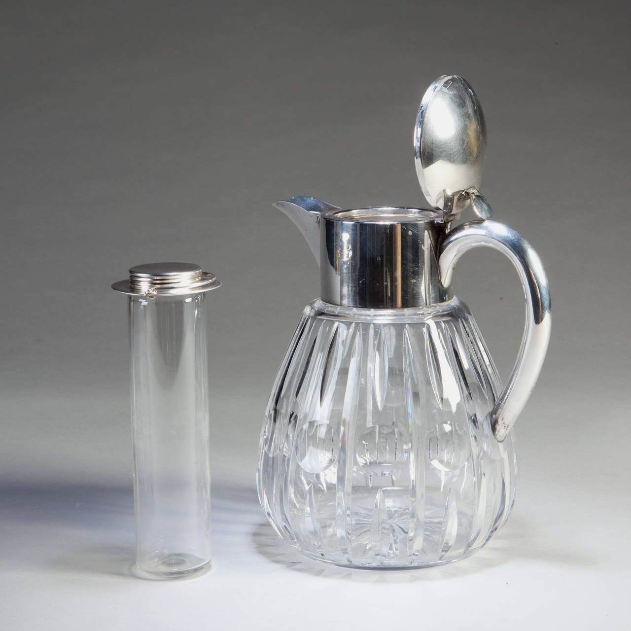 A large scale Edwardian cut-glass and silver plate lemonade jug having a boldly modeled handle, the top open to reveal a removable ice container. Indistinctly stamped under the handle.
