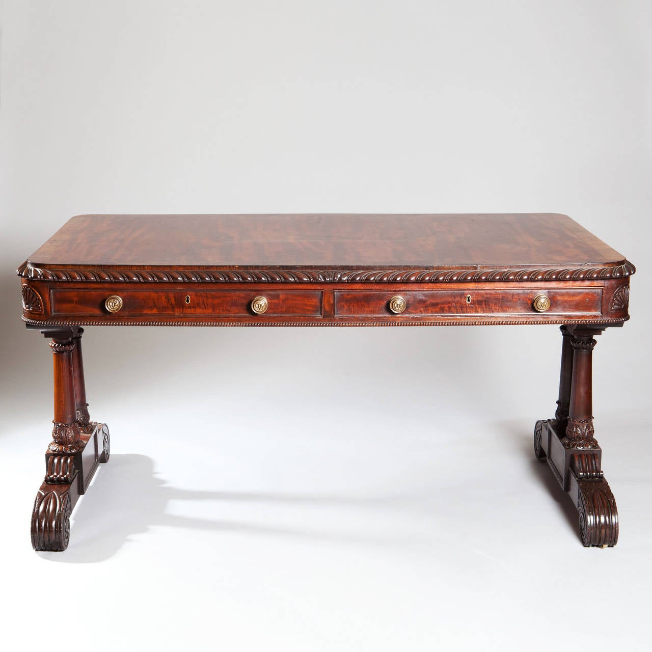 An exceptional early 19th century mahogany writing desk, finished in on all sides, the top with two long drawers in the front and two dummy drawers in the back between a thumb moulding of gadrooning and beading, the top supported on double column