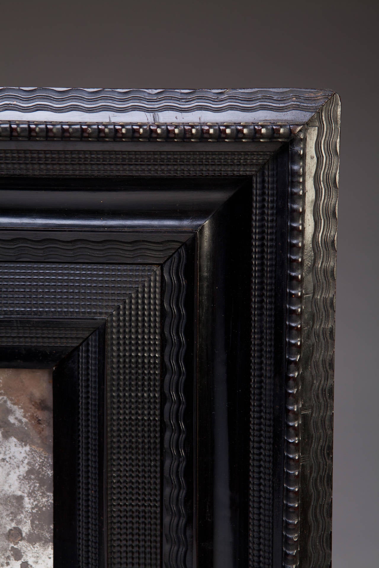 A large-scale early 18th century Dutch ripple moulded ebony mirror retaining its exceptional original mirror plate. 

During the 17th century cabinet-makers in the Southern Netherlands were decorating fine furniture with new and exciting