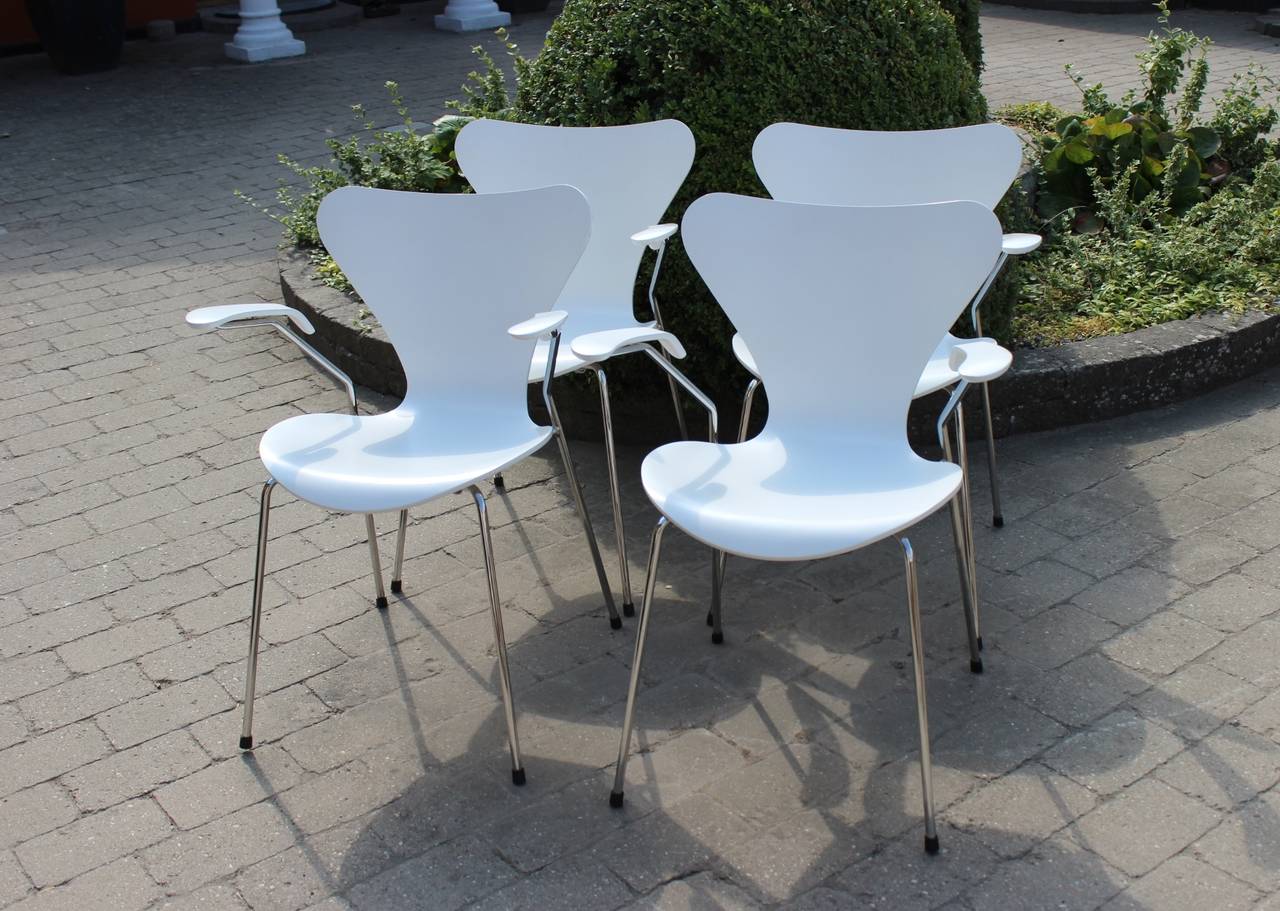 Four white "Series seven" chairs, model 3107, with armrests designed by Arne Jacobsen and manufactured by Fritz Hansen. The chairs were manufactured in 2008, but designed in the 1950s.