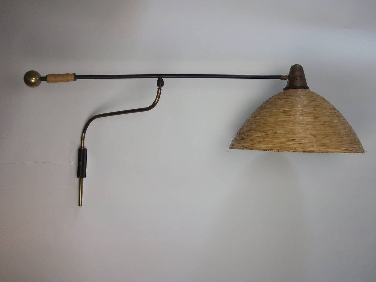 Incredibly well made and super unique Mid-century modern adjustable wall light. A real statement piece!!   Unknown maker and designer. Woven Rafia  shade and handle - quality brass and metal arm.
 Note: one small dent in one of the pics at the top