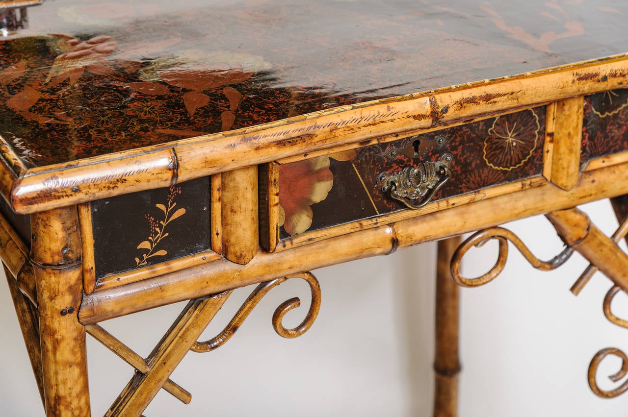 A fine petite English ladies desk with lacquered top painted with birds. The desk is appointed with a pair of  silvered top inkwells. The desk is outfitted with a single drawer .