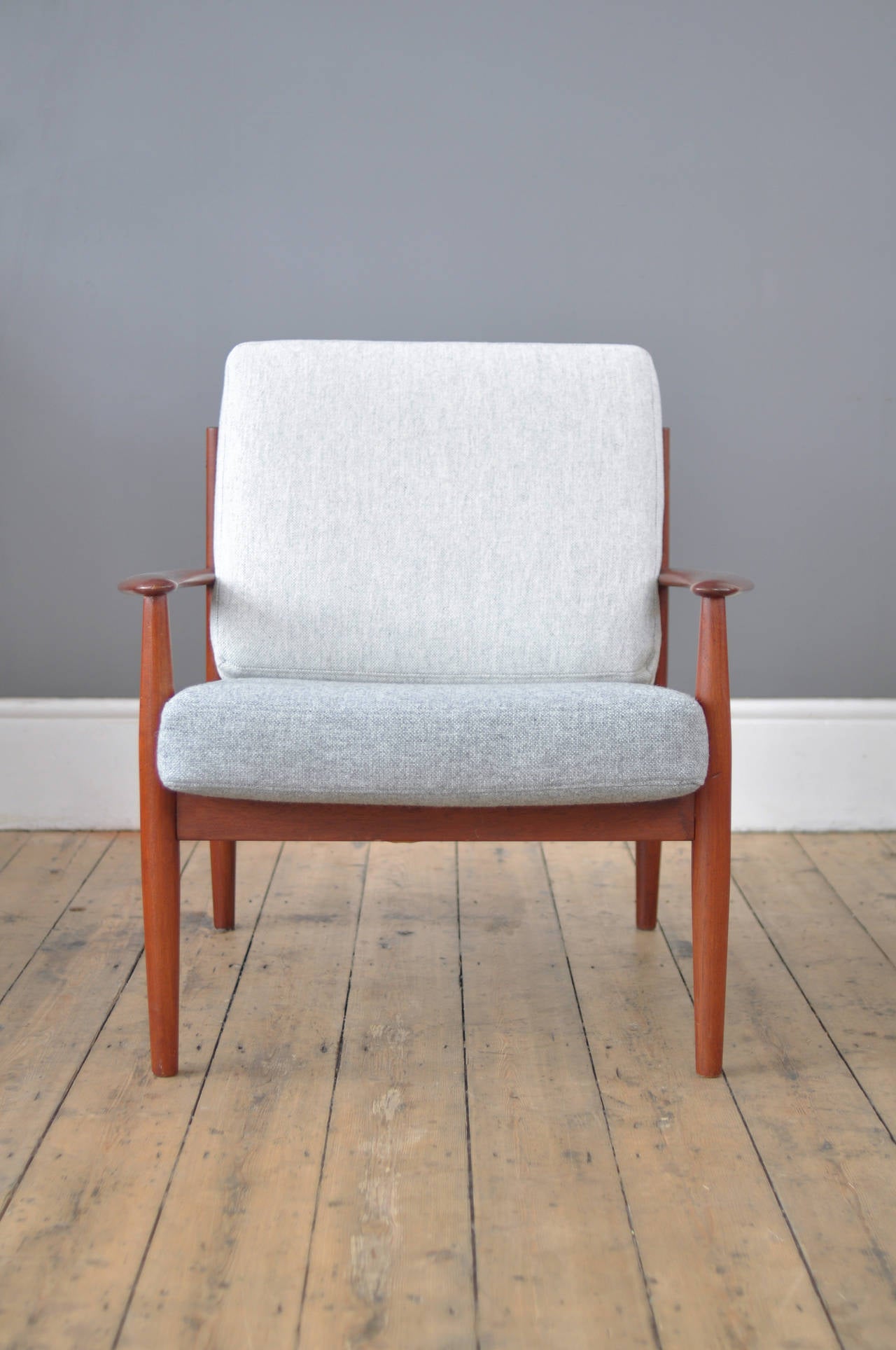 Armchair by Danish designer, Grete Jalk, featuring her trademark modernist simplicity. The teak frame, with its elegantly curved backrests and finely crafted armrests, attests to the masterful handling renowned of manufacturers, France & Daverkosen.