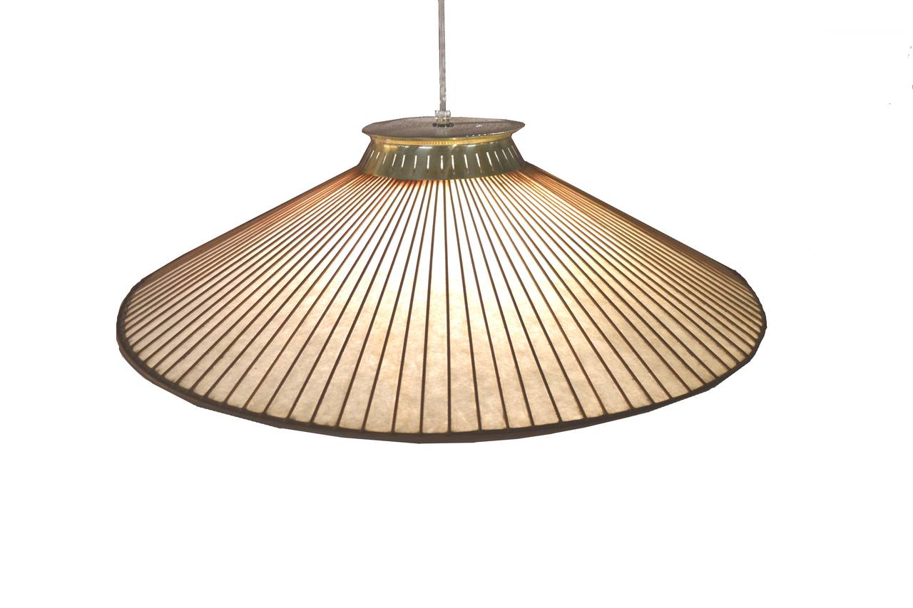 Asian-inspired, Mid-Century Modern Classic pendant lamp by Gerald Thurston for Lightolier with brass fittings and a fiberglass shade with walnut strips, circa 1957. The hanging length is adjustable with the metal weight; it lifts and lowers, extends