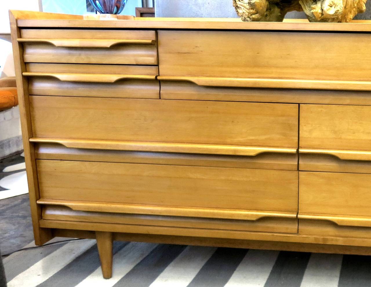 Unusual Crawford Furniture (Jamestown, NY) nine-drawer lowboy dresser from the 1950s made of honey and golden toned, finely aged solid maple. A bank of two large drawers on the bottom right and two on the bottom left are topped with a large center