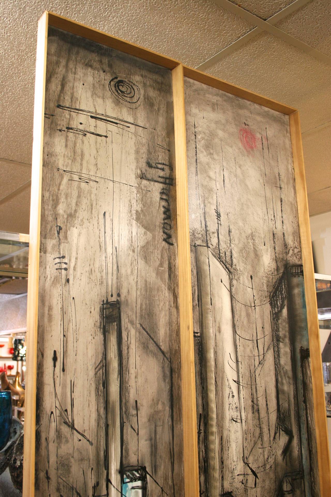 Tall, vertical abstract cityscapes painted on paper and attached to wood panels, framed with thin unfinished wood. These two versatile paintings may be displayed together or separately. The subdued gray, steel blue and cream color palette contrasts