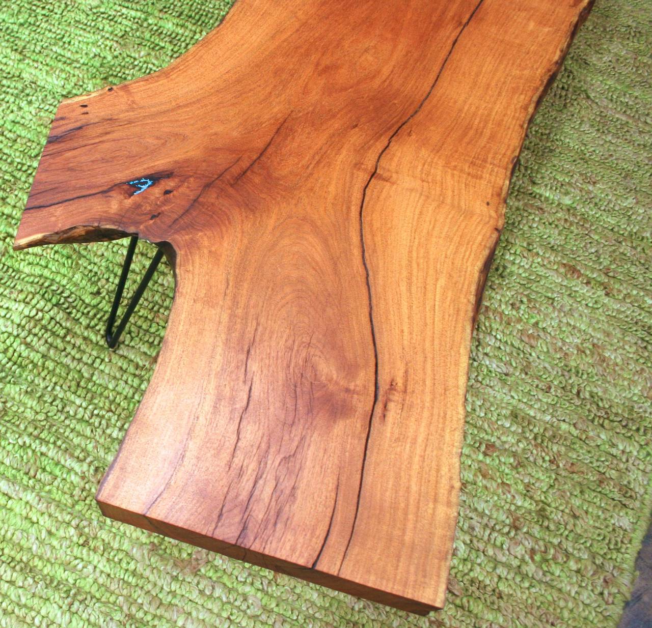 The unique shape of this solid mesquite slab coffee table is as distinctive as it is versatile. Beautiful depth of grain is brought out by a light stain. Live edge on the long sides, smooth truncated edges on the ends. Natural cracks have been