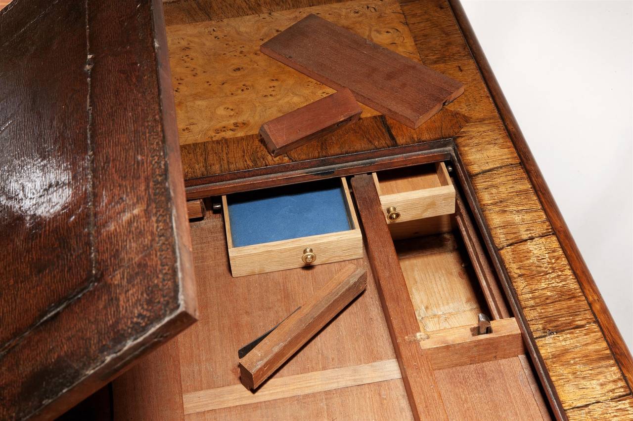 The lifting leather writing slope revealing an extraordinary arrangement of eight secret drawers, concealed by removable panels operated via concealed pressure points, the frieze with one long central drawer flanked by two short drawers on either