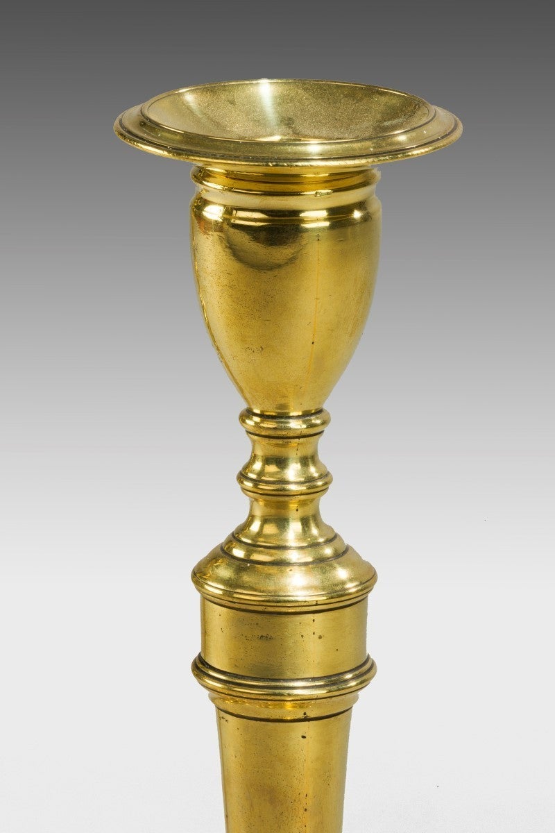 In brass, seamed, in neo-classical design. With loose nozzles on tapering stems and on a raised stepped base.

Bibliography: For a similar pair of candlesticks see Eloy Koldeweij, 'The English Candlestick: 500 Years in the Development of the