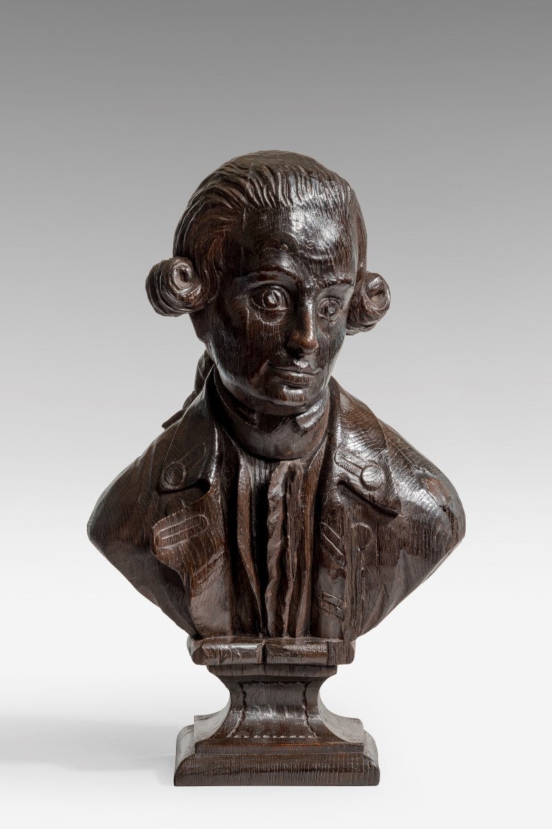 Made in England or America.

Modelled looking slightly downwards and to sinister, his hair tied back with curl at each temple. Wearing a shirt and a cravat beneath a coat with a buttoned collar and lapels. The lower section of the socle