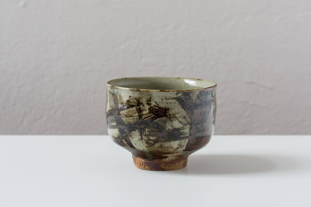 This ample sized chawan is brushed with an active, expressionistic kaki and iron underpainting.  Sturdy and firmly grounded with a high foot typical of Mashiko ware.   During the firing, a curtain of glaze peeled partially on the inside to reveal