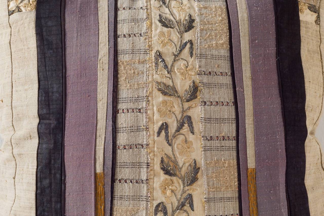 A central strip of a 19th C continental  silver work embroidery shown on the reverse side composed with vintage Kente cloth, Tsumugi silk and Huang Ping Miao cotton and embroidery and Miao hemp. Also on the reverse side are the bronze pieces of a