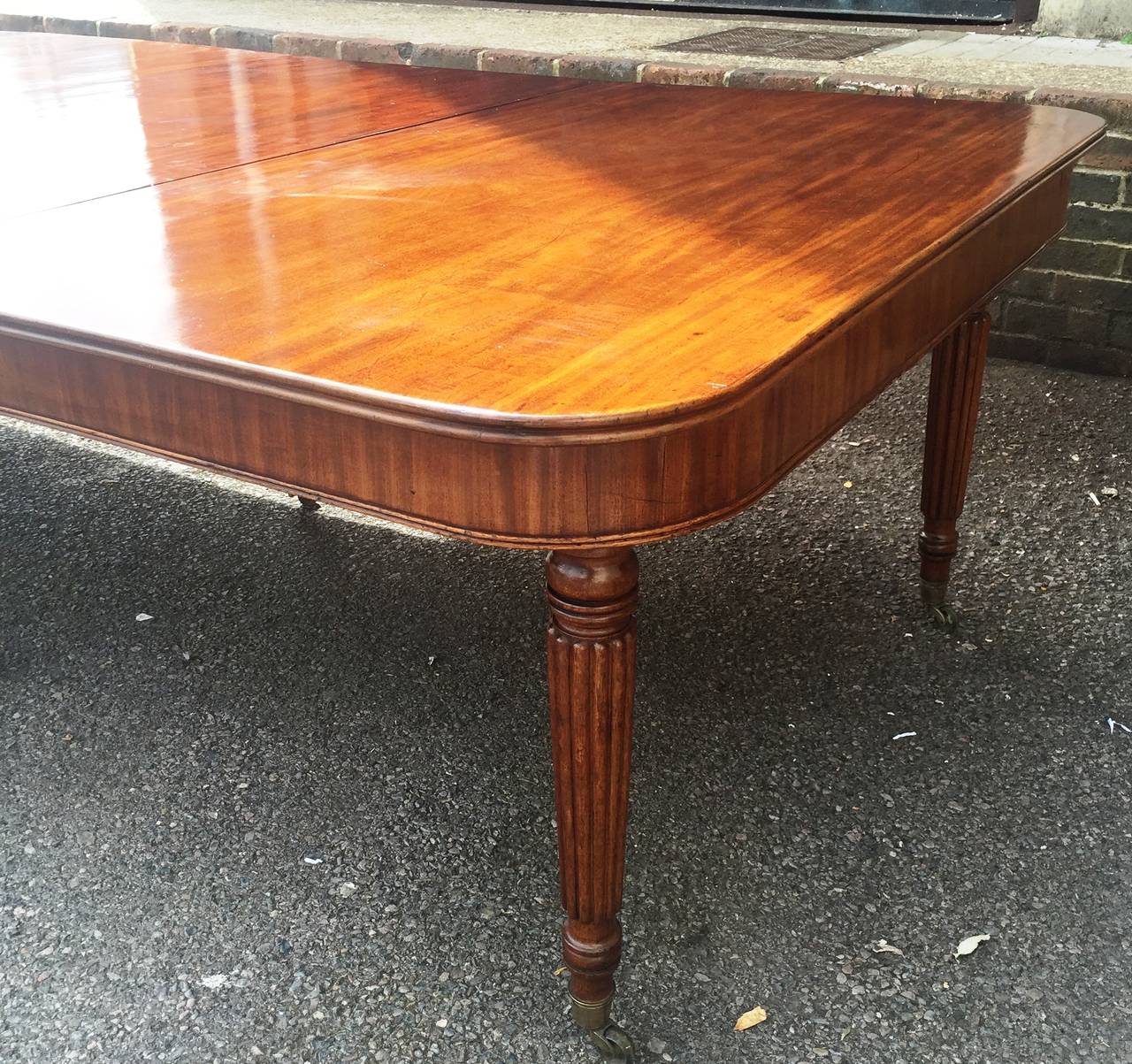 A very good quality late Regency period, Gillows influenced mahogany extending dining table, having three original leaves, a wonderful faded patina to all. Raised on turned reeded legs and terminating in the original brass bucket castors. Extends to
