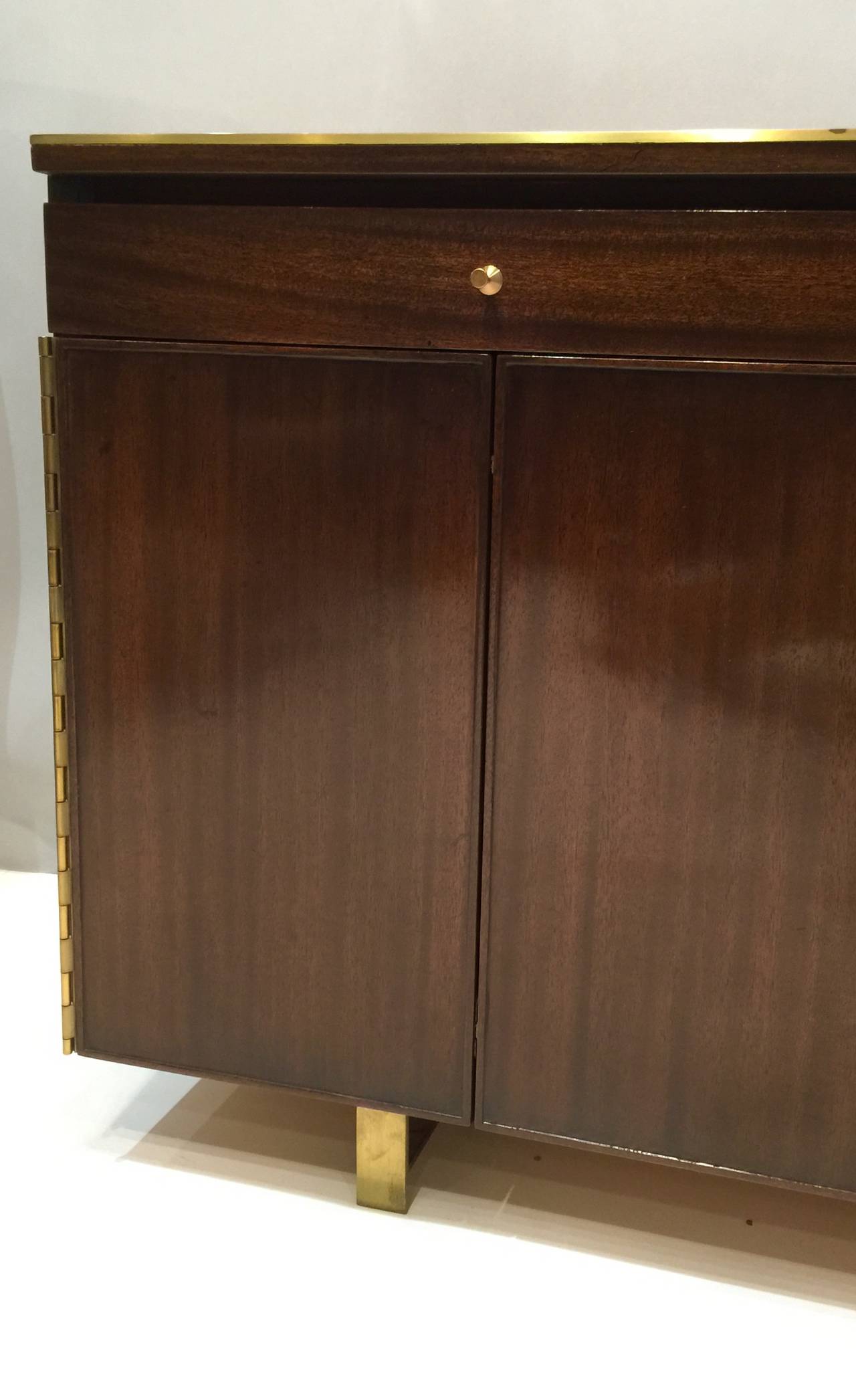 A Paul McCobb Credenza For Calvin Trimmed In Brass On Brass Legs.  Three Drawers Over A Pair Of Trifold Doors That Conceal Shelving On The Left And Drawers On The Right