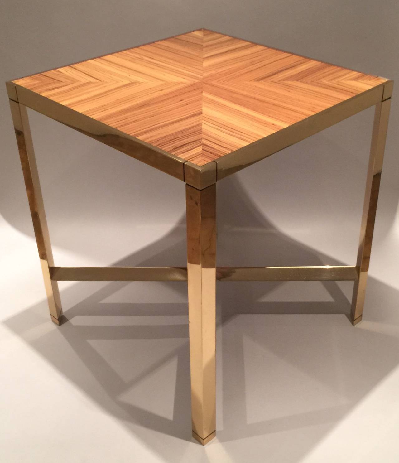 A 'Triangular Leg Metal End Table ' by Karl Springer in brass with a zebra wood veneer inset top.  Table is accompanied by a letter of authentication