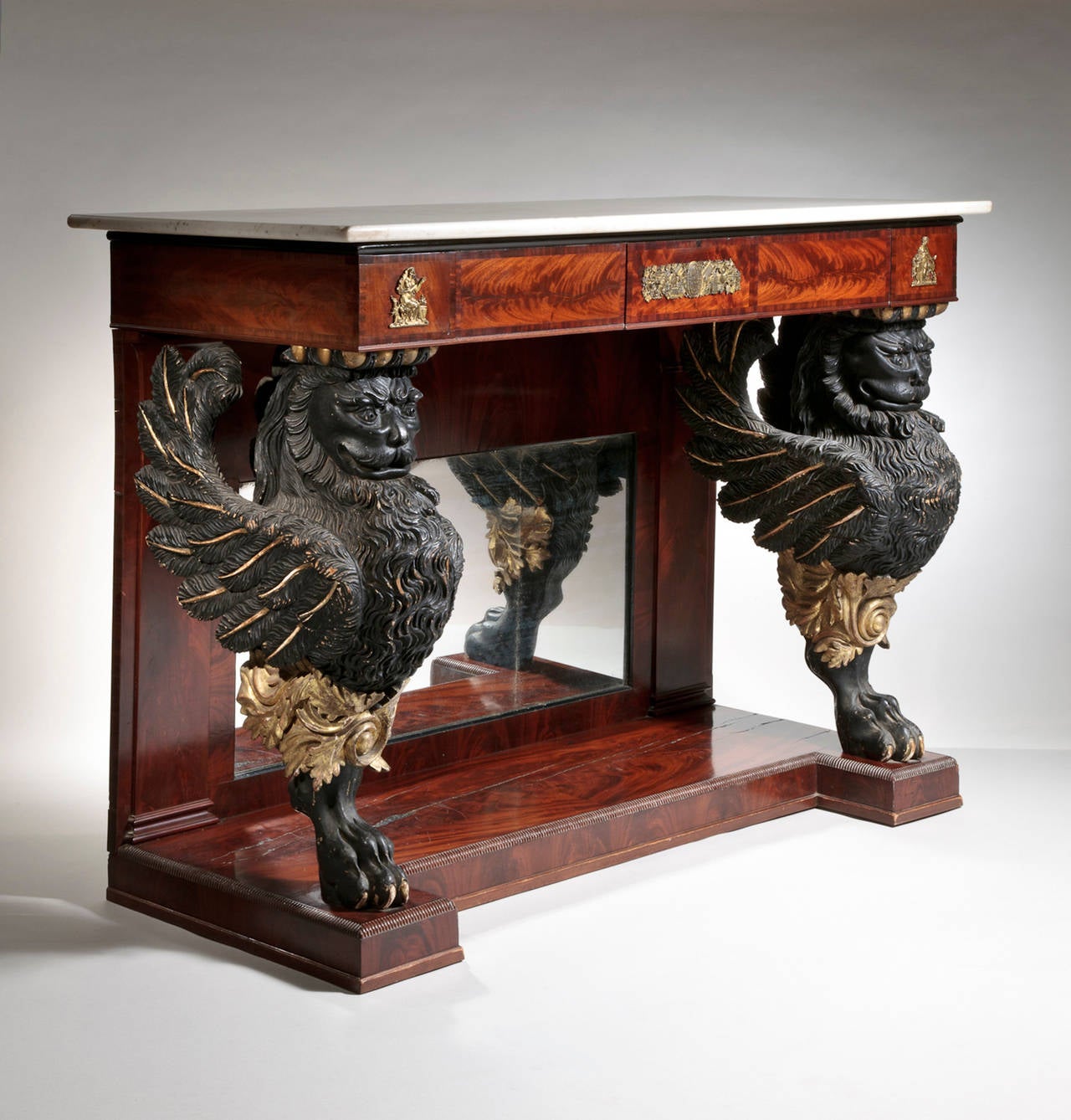 A Philadelphia Empire crotch mahogany veneered marble-top pier table with carved paint and gilt decorated winged lion supports. The Carrara marble top over a frieze of bookmatched crotch mahogany panels, further framed with mahogany crossbanding and