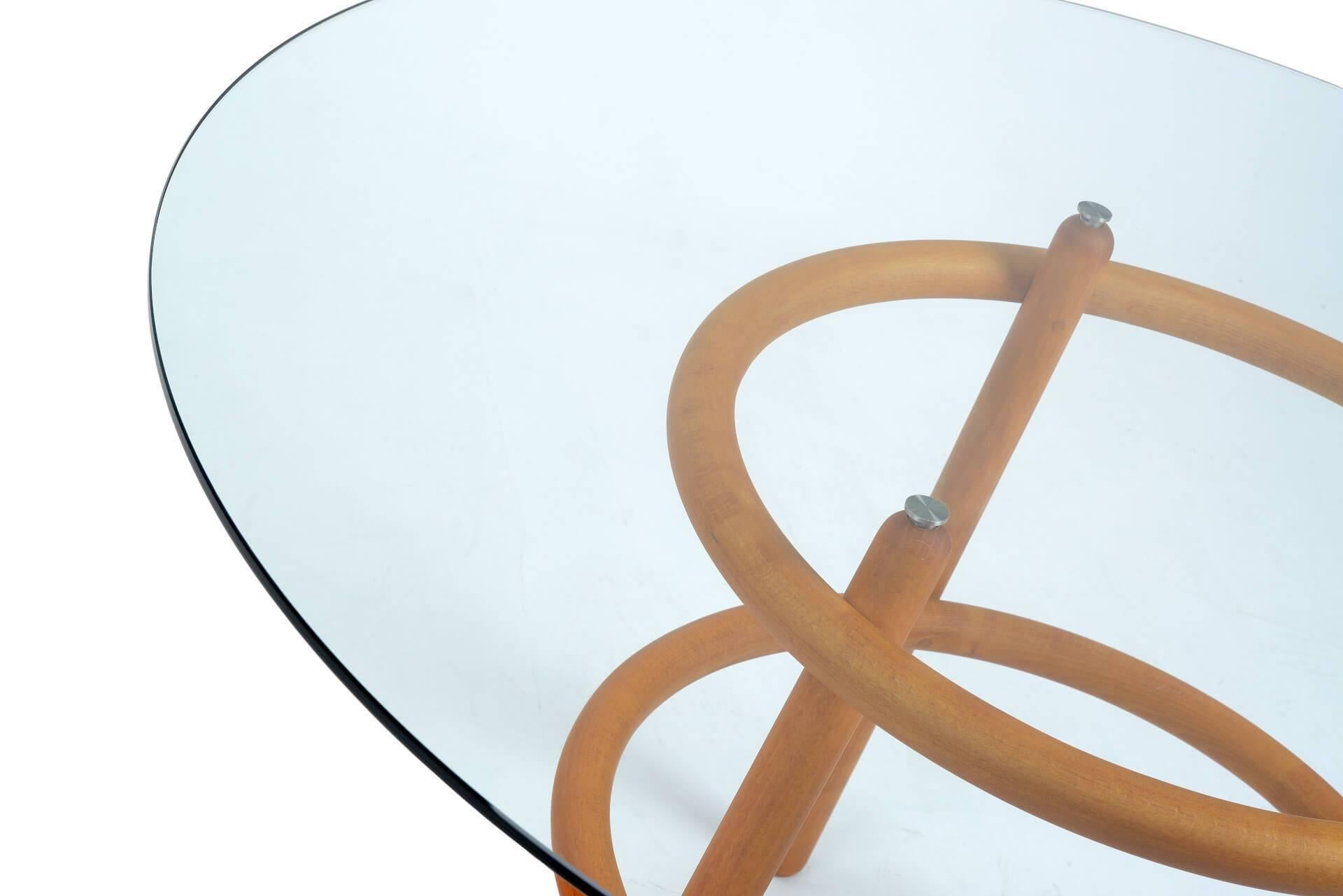 Support structure in solid beech with round section elements. The base is made up of three legs intersected by two hoops of the same diameter. The round, flush top is in extra clear transparent glass.