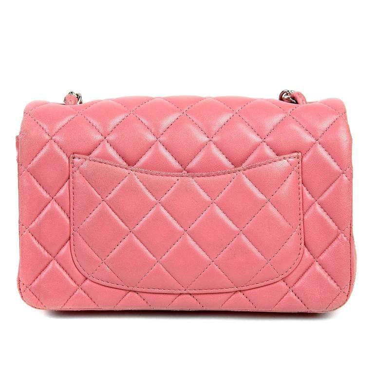 This Authentic Chanel Pink Lambskin Mini Classic is in better than excellent condition. The pretty pink shade adds an extra dash of femininity to any ensemble. Carnation pink lambskin is quilted in signature Chanel diamond stitched pattern. Silver