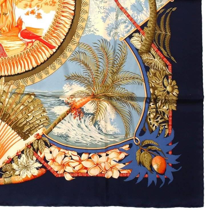 This authentic Hermes Blue and Orange Aloha 90 cm Silk Scarf is new with the original box. Originally designed by Bourthomieux in 2000, the print features a navy blue border with vibrant orange center design. Tropical theme with palm trees, exotic