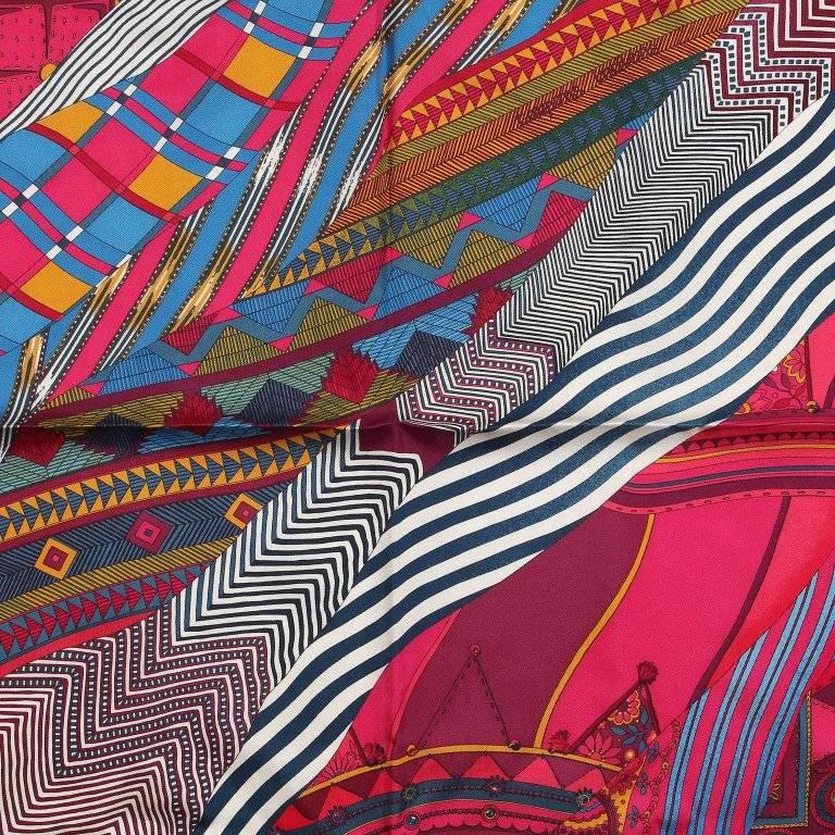 This authentic Hermes Coupons Indiens Pocket Square Silk Scarf is pristine. Artist Ailine Honore and issued in 2008. Swirling patterned fabrics in shades of fuchsia, burgundy and blue. 100% silk. 
A238