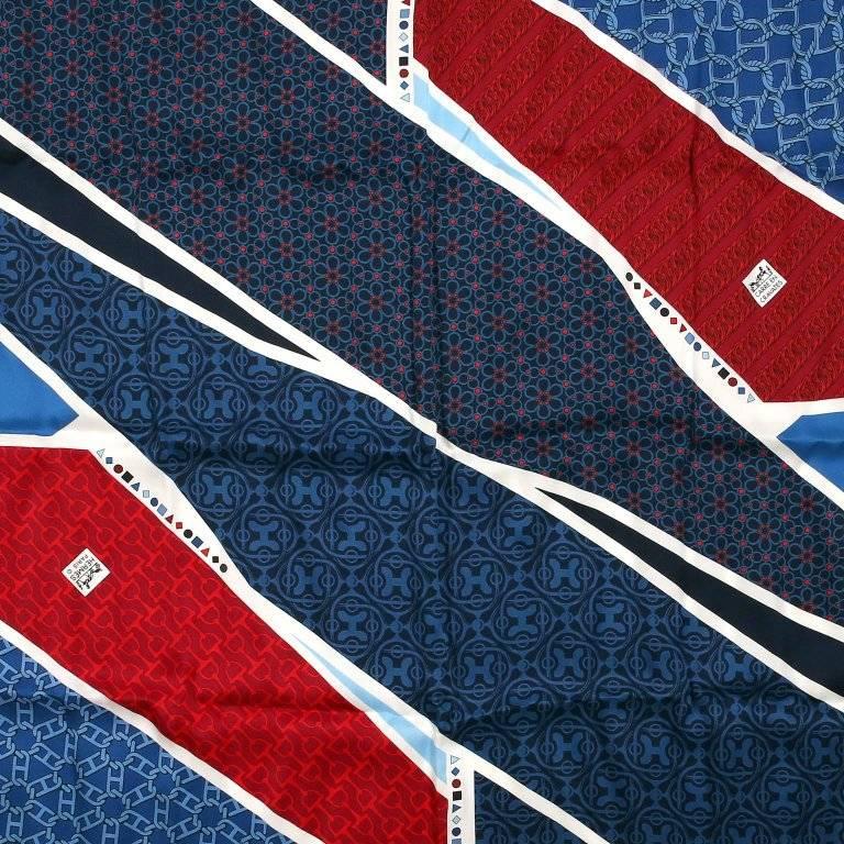 This authentic Hermes Carre en Cravates 60 cm Silk Scarf is new. Issued in 2011, the navy blue, red and white colorway features swaths of patterns. Chaine d'ancre, stirrups and H logos create individual designs. Made in France. 100% silk. 
A245