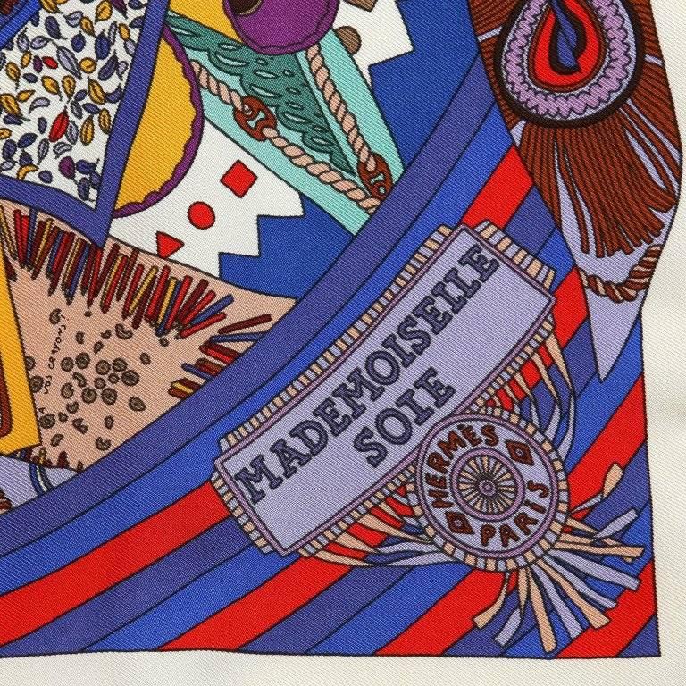This authentic Hermes Mademoiselle Soie Silk Pochette Scarf is new with the box. Designed by Pierre Mari and issued 2011. Blue and red multi colored pattern features a woven braided seamstress with her tools in hand. Scissors, threaded needle and