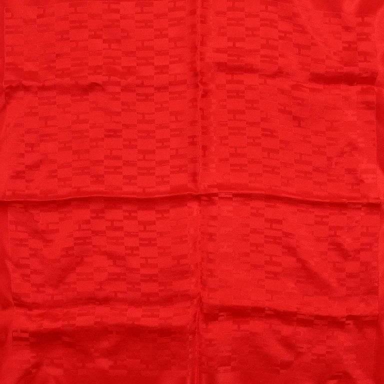 This authentic Hermes Red Op‚ÄôH Silk Pochette Scarf is new. Bright red jacquard with a kaleidoscope pattern of the letter H. A tribute to the optical art movement. Made in France. 100% silk. 
A281