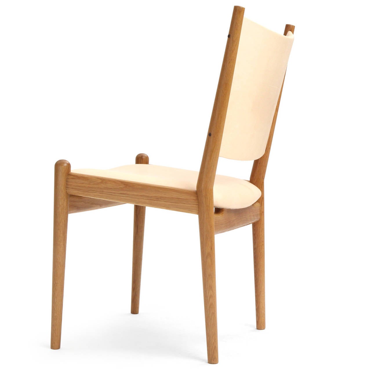 A superbly crafted dining chair largely devoid of extraneous detailing, having exposed oiled white oak frames with gently curved backs and tapered dowel-form legs and natural leather upholstery.