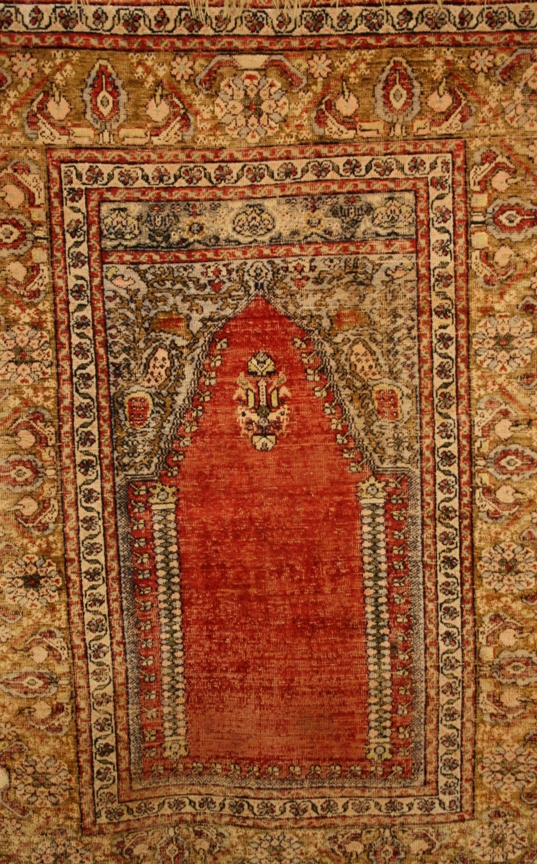 This is an antique Turkish silk prayer carpet. It was woven in the workshops of Kayseri in Central Anatolia. Tis piece has a classic design and color combination. The rich vegetal dyes used give this piece a very rich saturated depth. The border is
